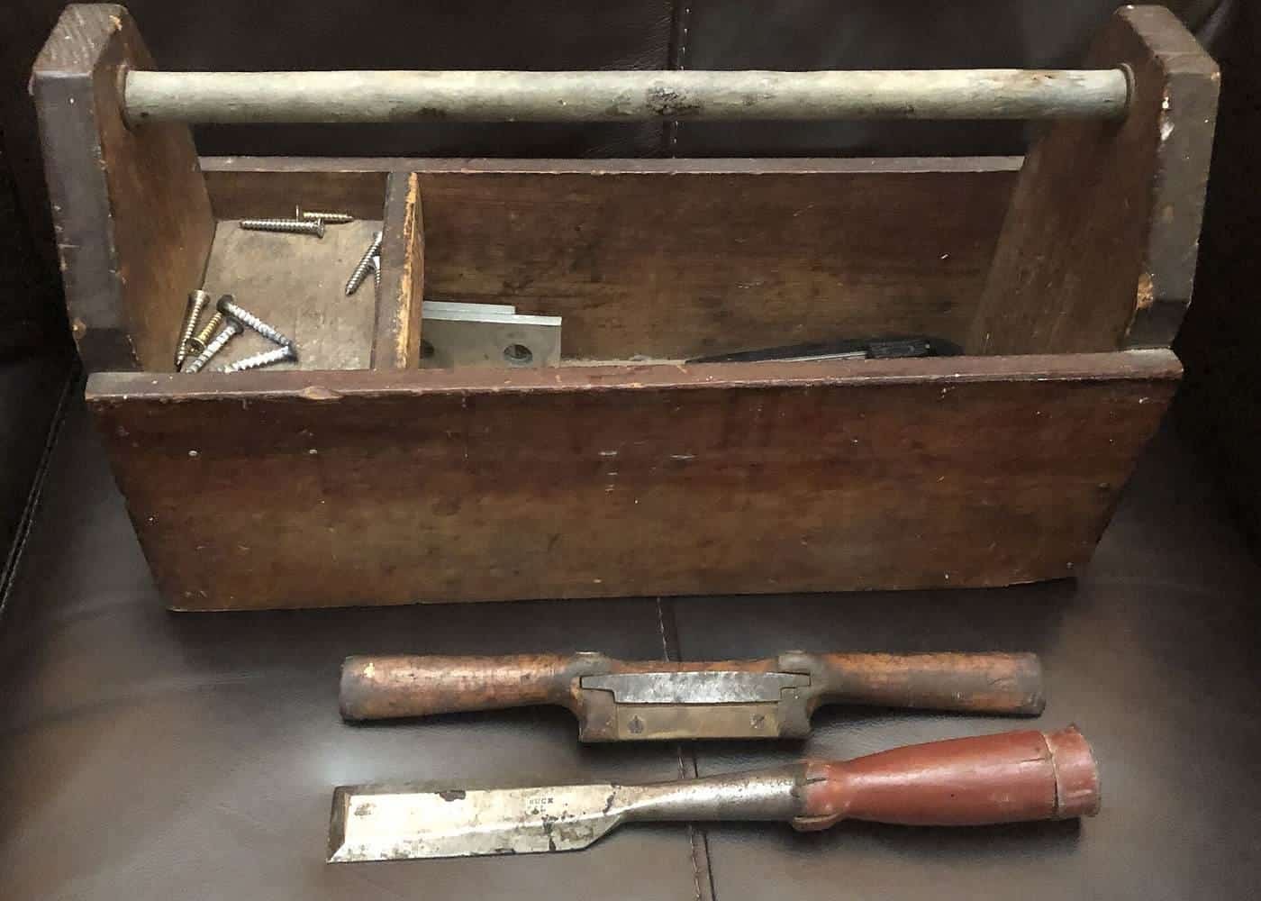 Open wooden toolbox with a chisel and a scraper