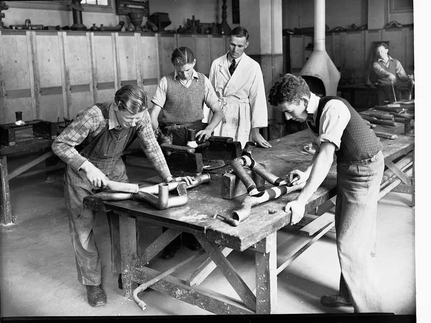 Historic photo of trade students working on pipes at benches