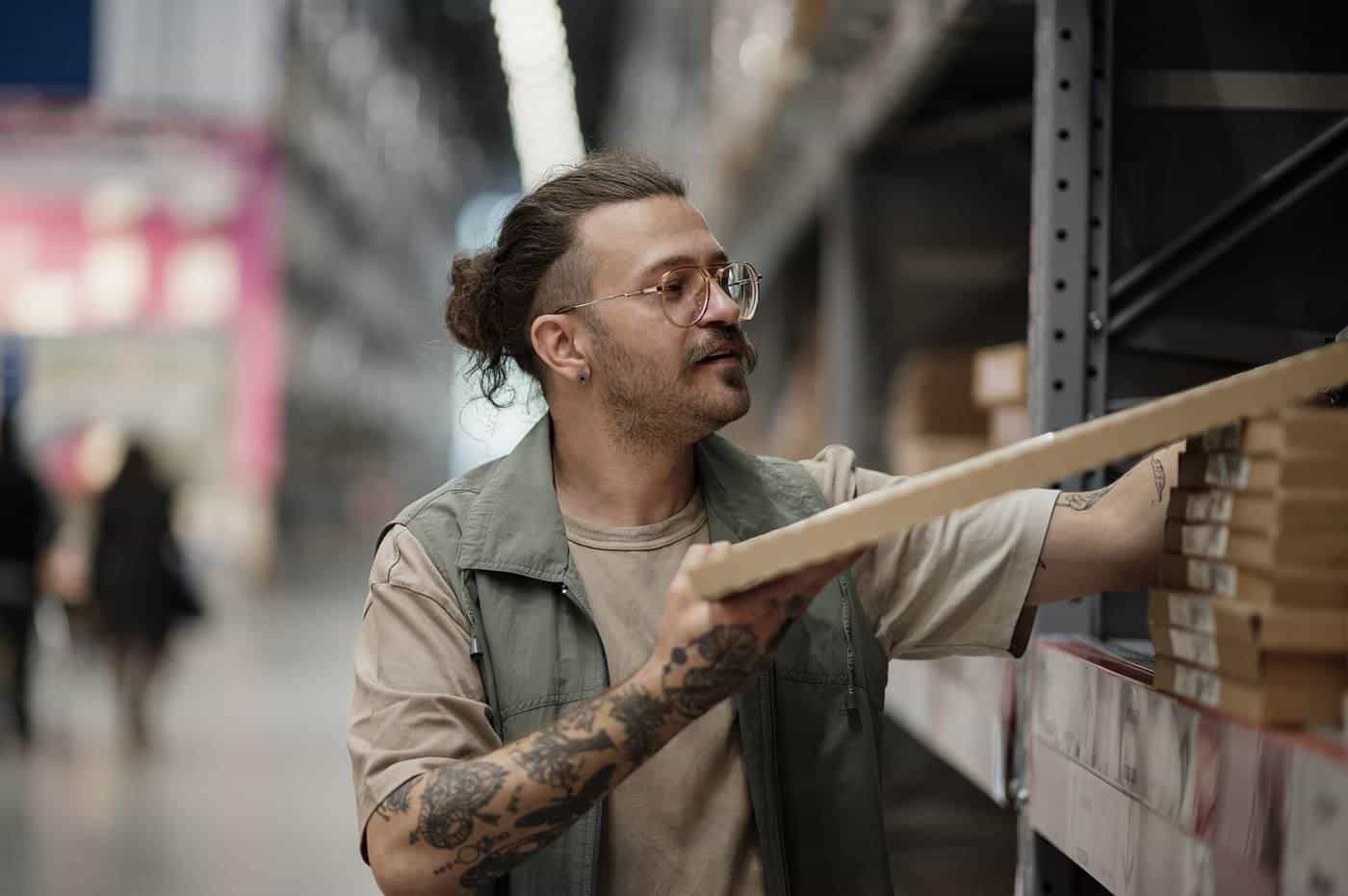 Man selecting wooden planks from shelves in a hardware store
